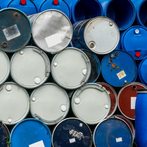 Old chemical barrels. Blue and red oil drum. Steel and plastic oil tank. Toxic waste warehouse. Hazard chemical barrel with warning label. Industrial waste in drum. Hazard waste storage in factory.